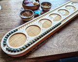 Beads cradled in 108 divots of wood mala board: a mala meditation necklace being made.