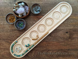 Aerial view of mala board being used to design beaded mala meditation necklace, with bowls of beads and crystals nearby.